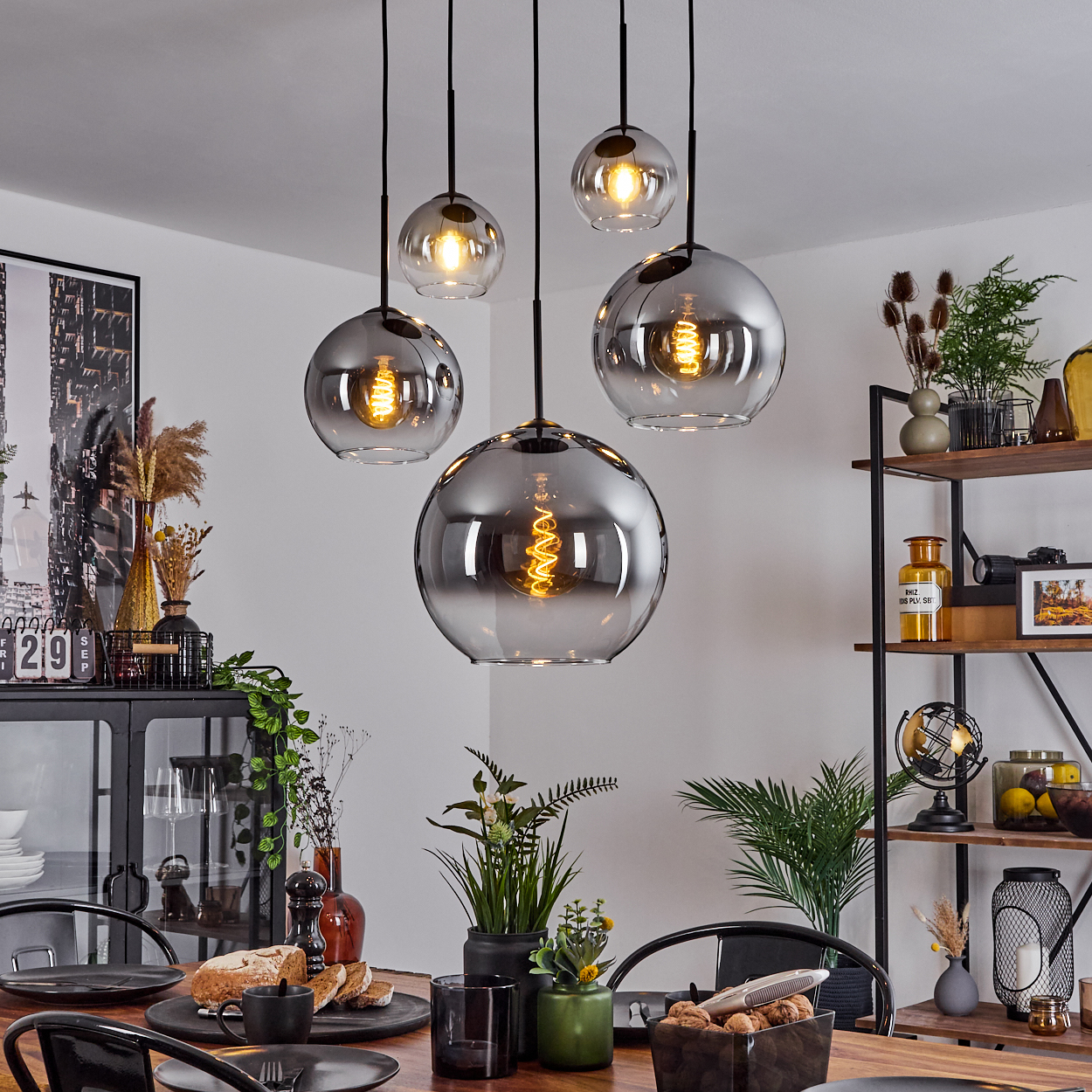 Esszimmer mit hängenden Kugelleuchten. Tisch mit Essen, Pflanzen und einem New York City Kunstdruck gedeckt.