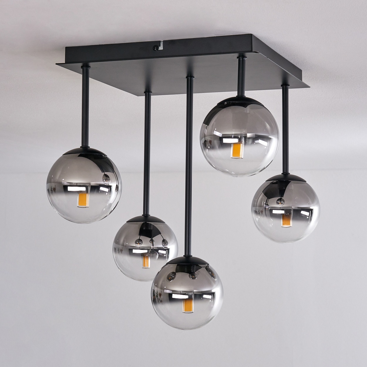 Eine Deckenlampe mit fünf kugelförmigen, verspiegelten Glasschirmen, die von einer weißen Decke hängen.