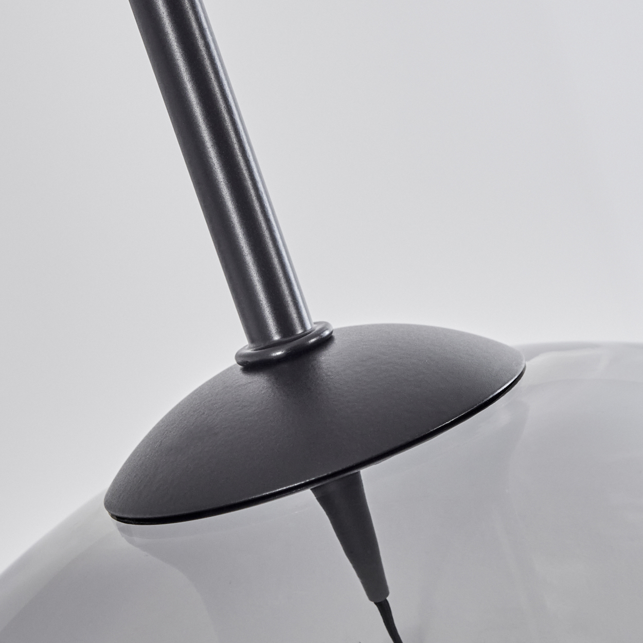 Nahaufnahme eines schwarzen Lampenständers und einer Glaskugel. Die Lampe ist modern und hat ein schlankes Design.
