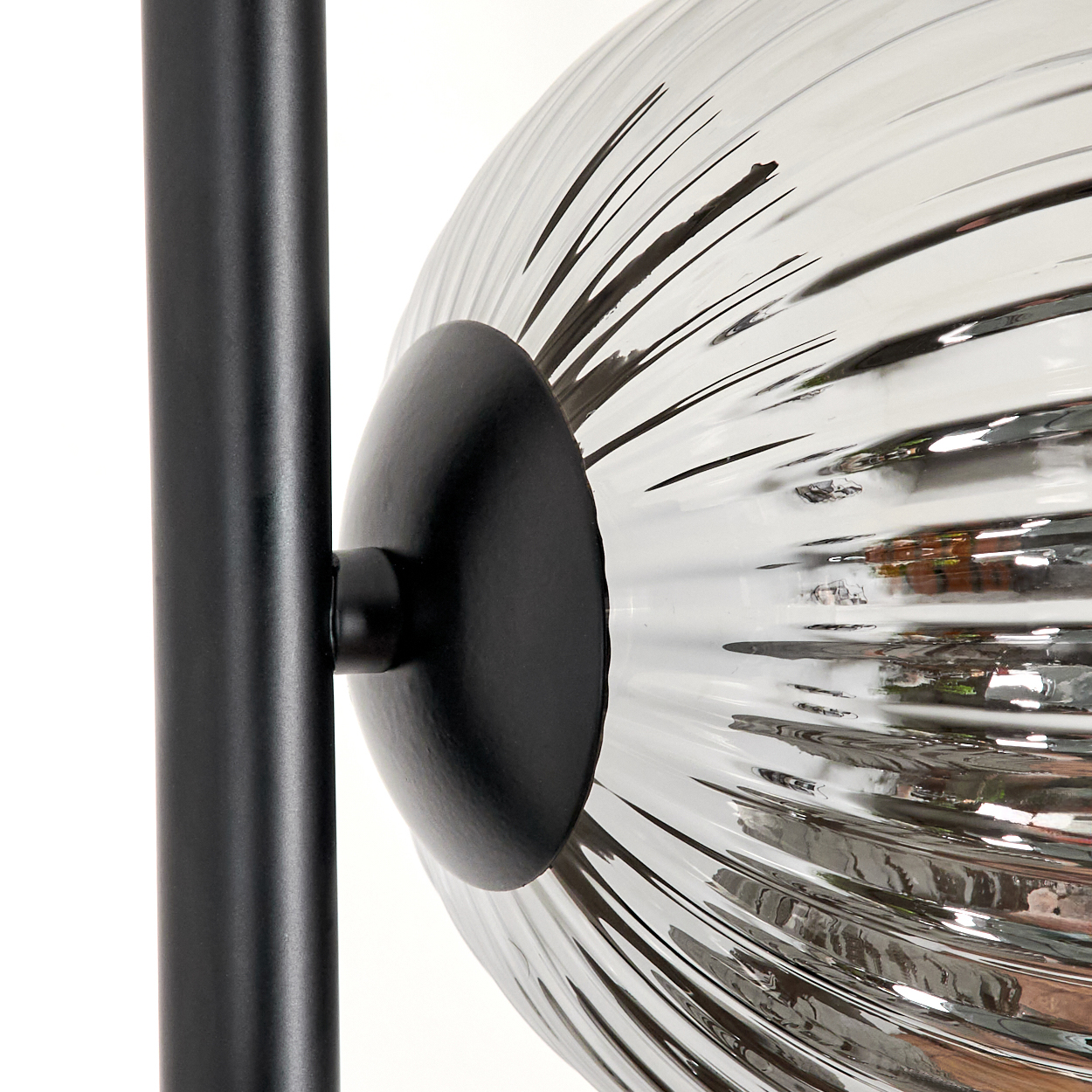 Nahaufnahme einer Stehlampe. Die Kugel ist geriffelt und transparent, mit schwarzem Stiel.