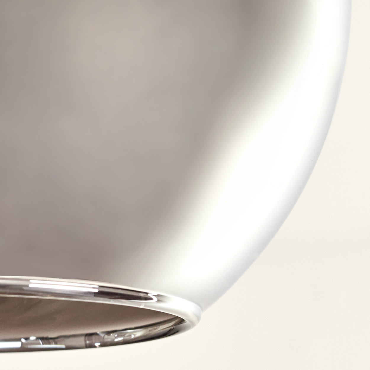 Nahaufnahme einer verspiegelten Glaskugel, die Licht reflektiert. Am Boden ist ein Chromrand sichtbar.
