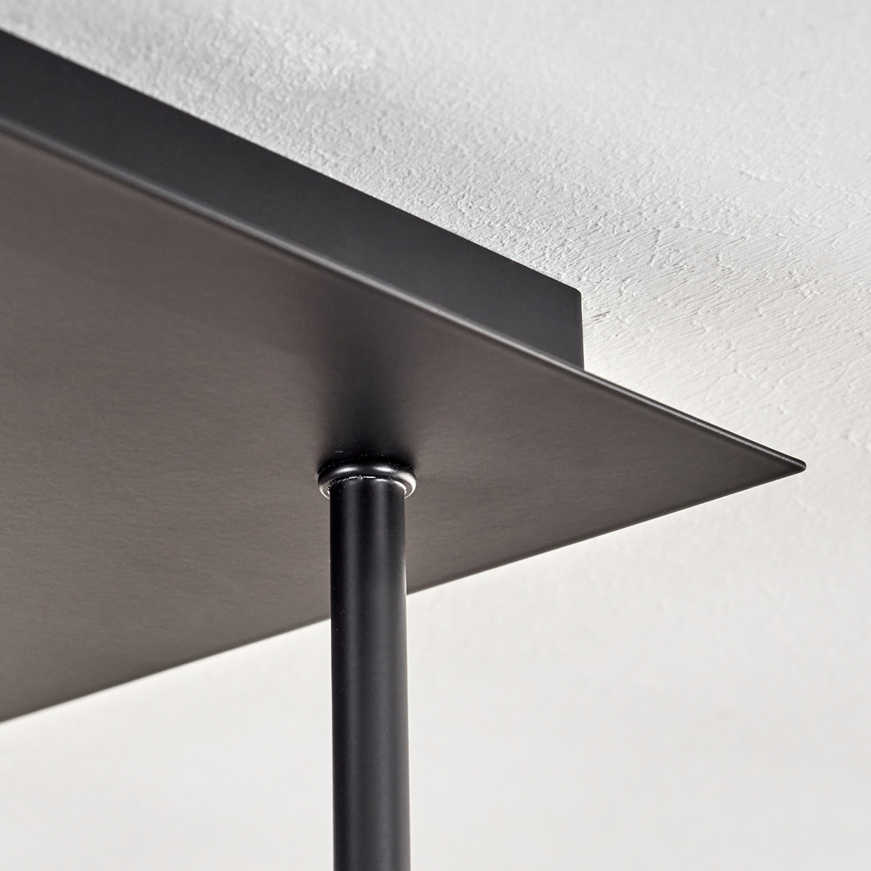 Eine Nahaufnahme einer schwarzen Deckenleuchte aus Metall vor einer weißen Decke. Minimalistisches Design.