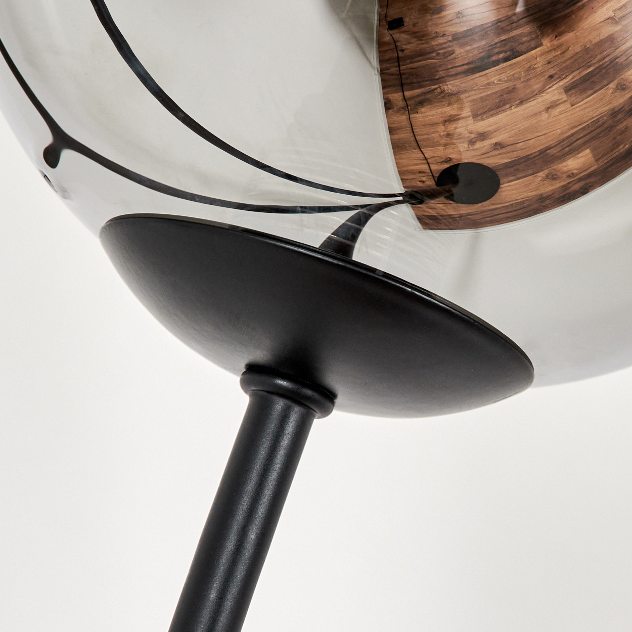 Nahaufnahme einer Lampe mit Glasschirm, zeigt Holzstrukturen als Reflexion im Glas.