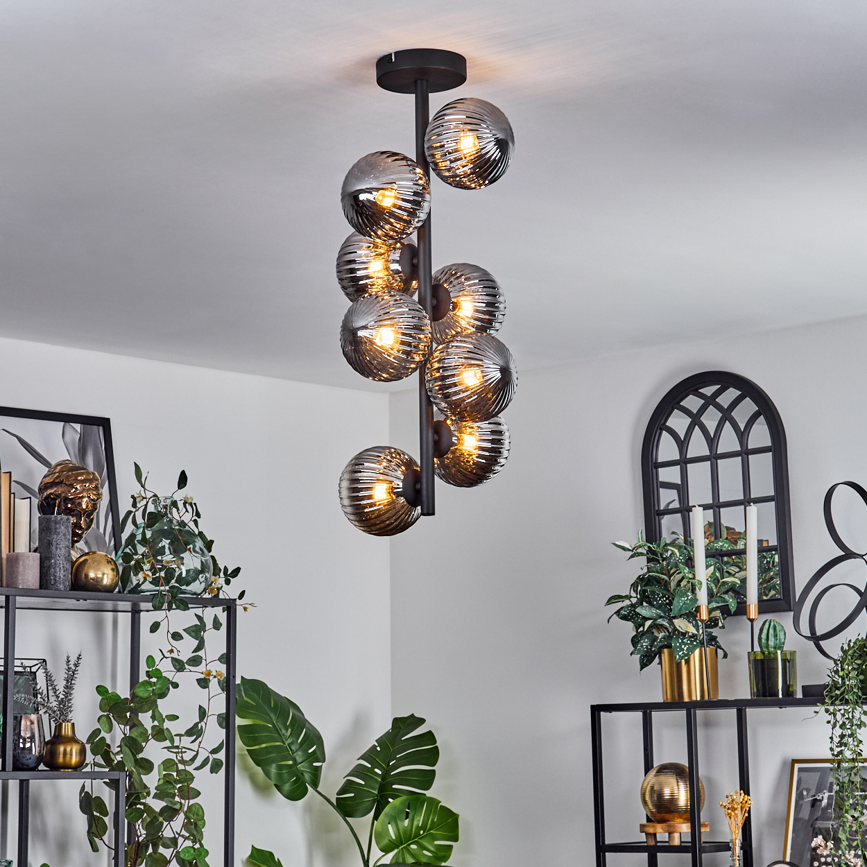 Eine schwarze Deckenlampe mit neun kugelförmigen, geriffelten, klaren Glühbirnen, die einen Innenraum beleuchten.