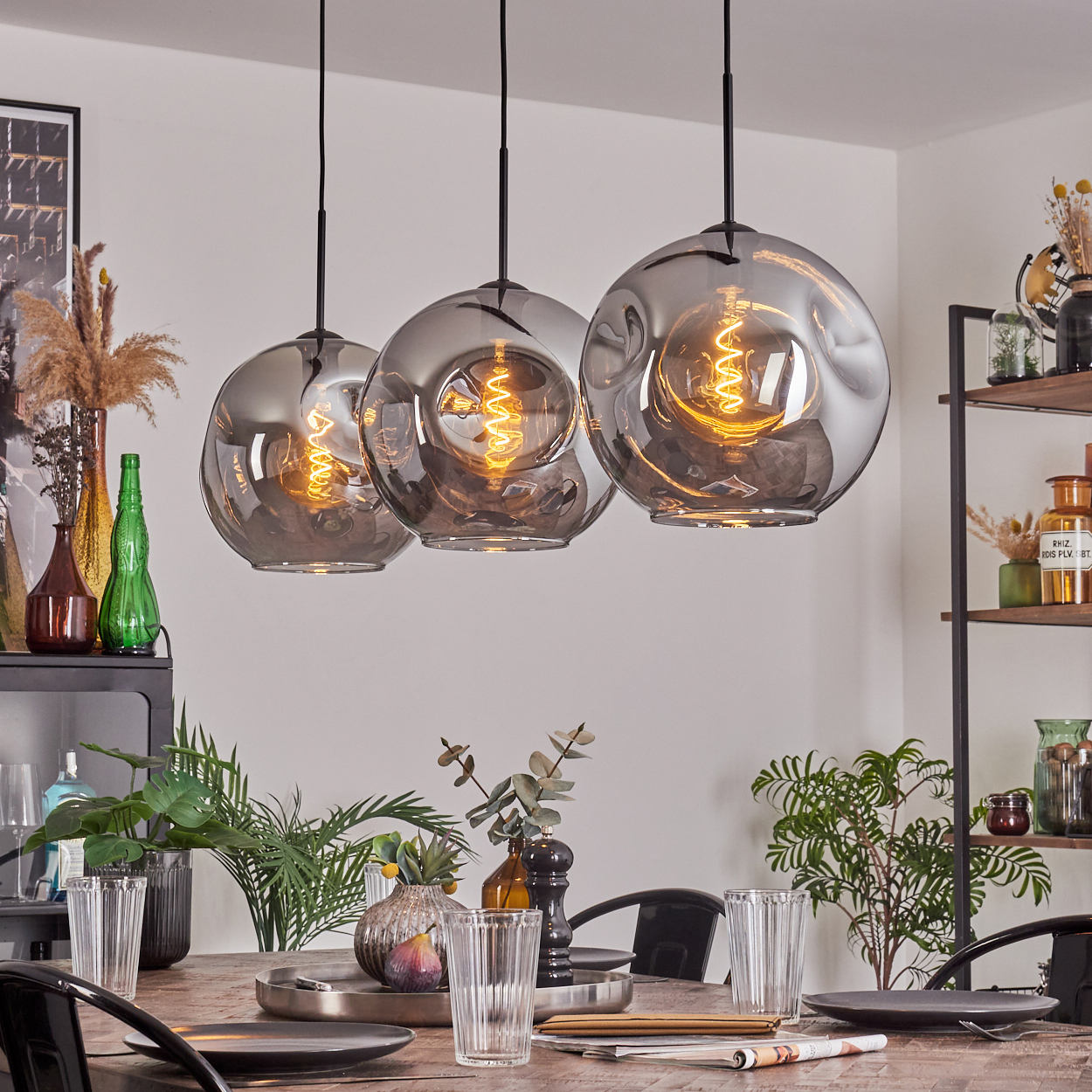 Drei Pendelleuchten mit runden, rauchigen Glasschirmen, jede mit einer sichtbaren Edison-Glühbirne.