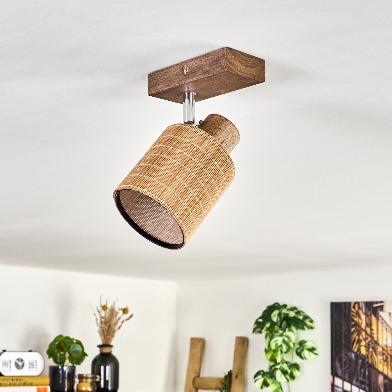 Ein Holzrahmen-Spotlight mit einem gewebten, zylindrischen Schirm, der von einer weißen Decke hängt.