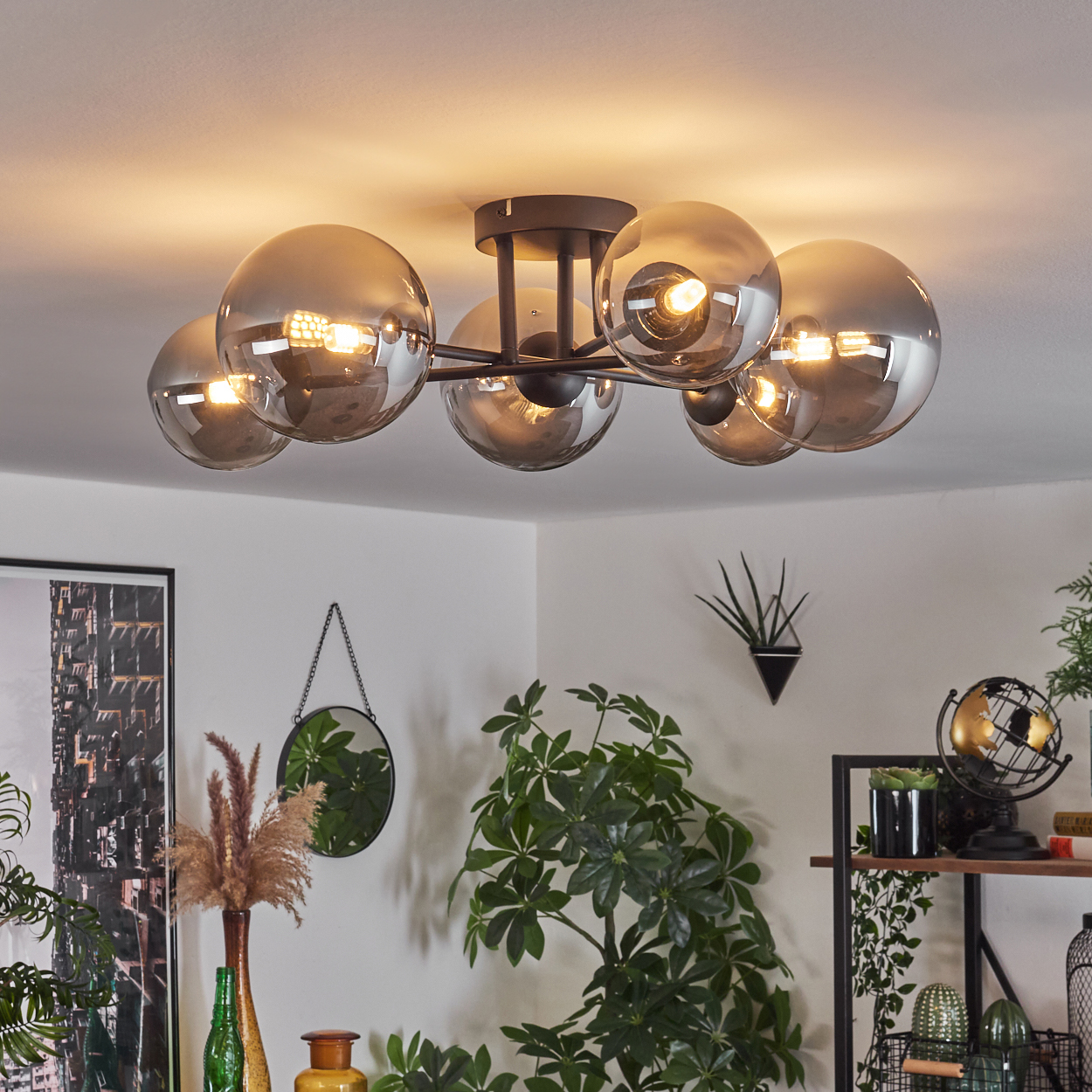 Eine Deckenlampe mit sechs verspiegelten Kugeln. Sie ist in einem Raum mit Pflanzen und Deko installiert.
