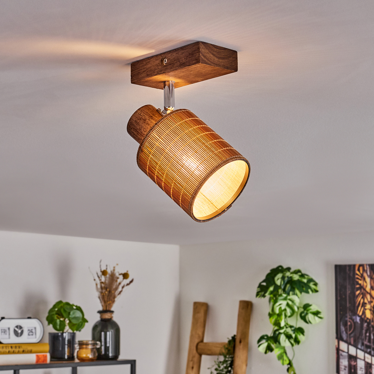 Ein Deckenstrahler aus Holz und Bambus. Er ist an einer Holzbasis befestigt. Das Licht ist an.