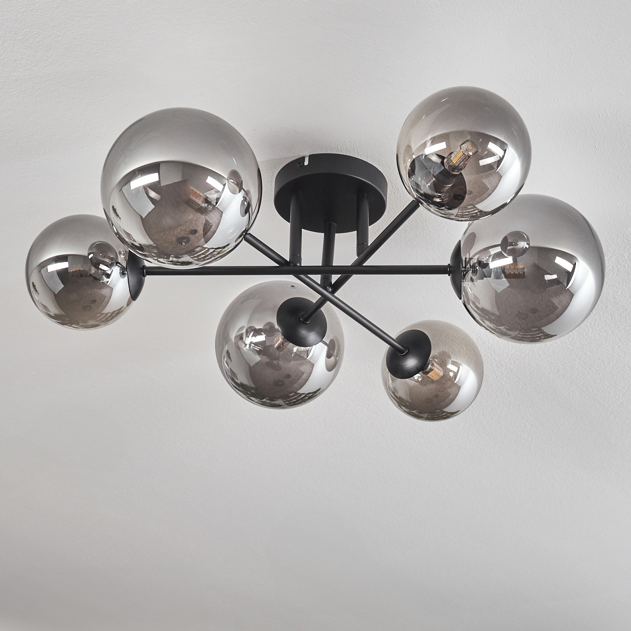 Eine Deckenlampe mit sechs verspiegelten Kugeln. Die Lampe ist an einer weißen Decke montiert.
