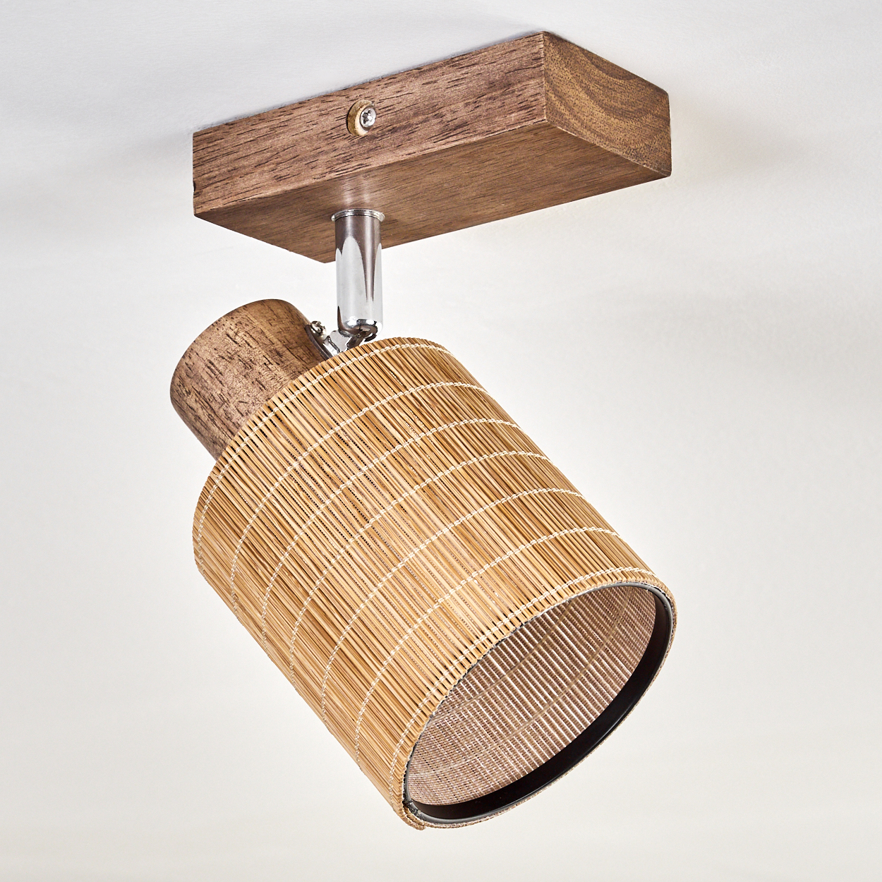 Ein Holz-Spotlight mit Rattan-Schirm, montiert auf einem Holzsockel, abgewinkelt, um Licht zu lenken.