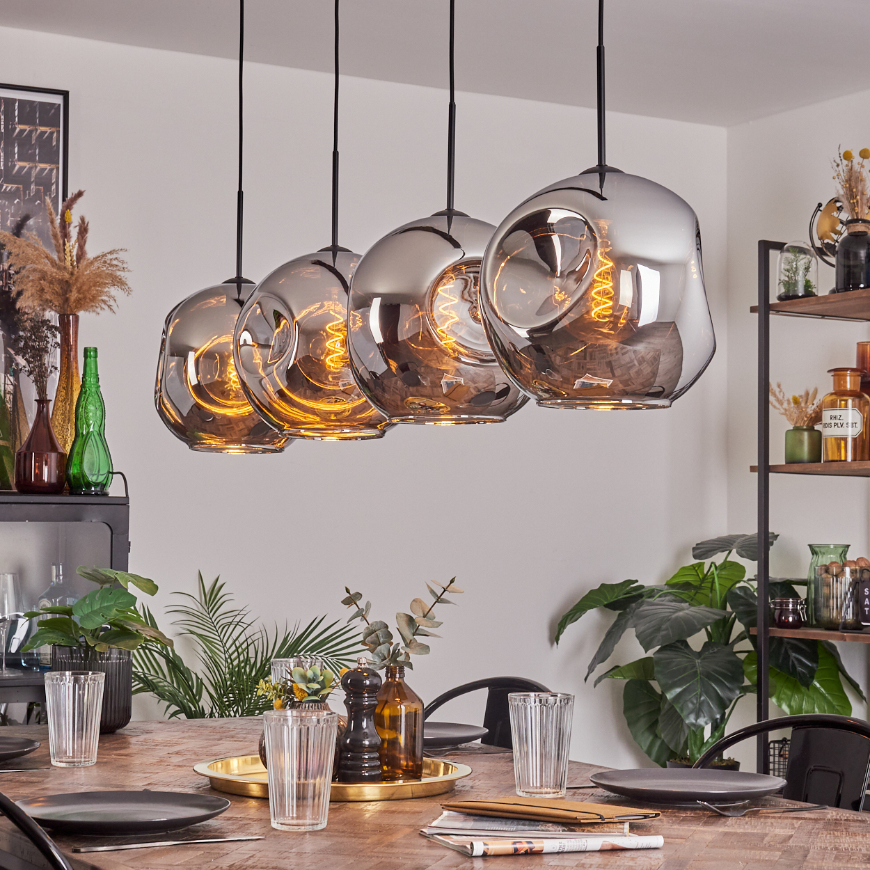 Ein Esszimmer mit vier Pendelleuchten mit verspiegelten Schirmen und sichtbaren Glühbirnen.
