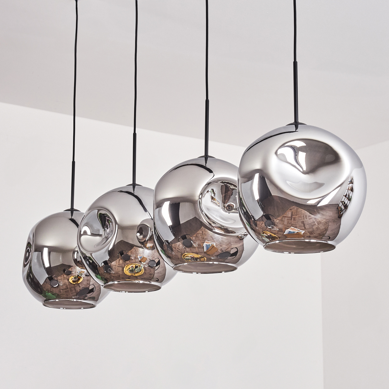 Vier Pendelleuchten mit verspiegelten Kugeln, die von der Decke hängen. Die Lampen spiegeln die Einrichtung des Zimmers wider.