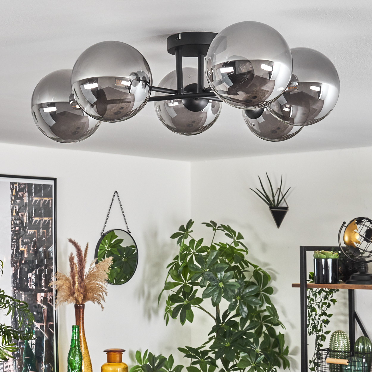 Deckenleuchte mit sechs silbernen Kugeln. Zimmer mit Deko: Pflanzen, Spiegel und Globus.
