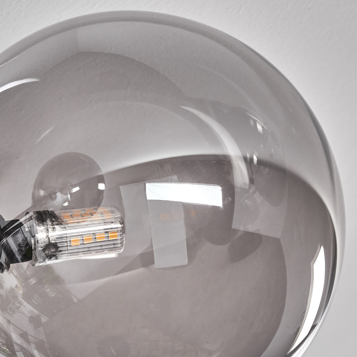 Nahaufnahme einer silbernen Glühbirne. Das Glas reflektiert das Licht, der Glühfaden ist sichtbar.