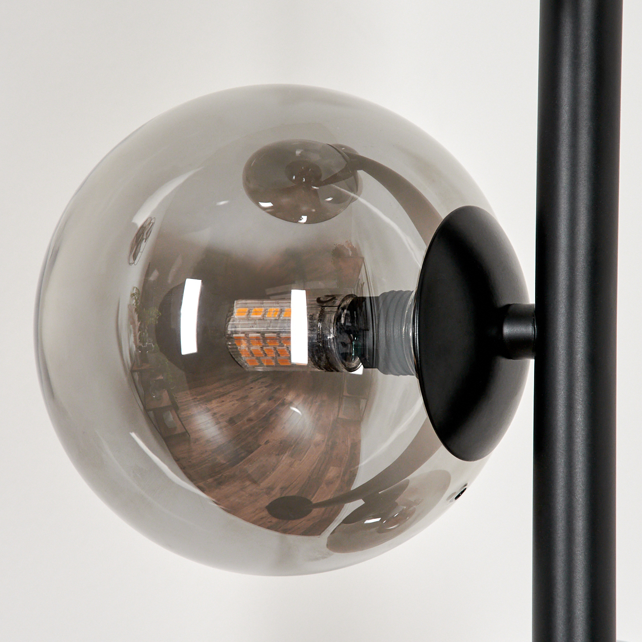 Nahaufnahme einer Glühbirne in einem Glaskugel, mit dem schwarzen Stiel und der Basis einer Lampe.