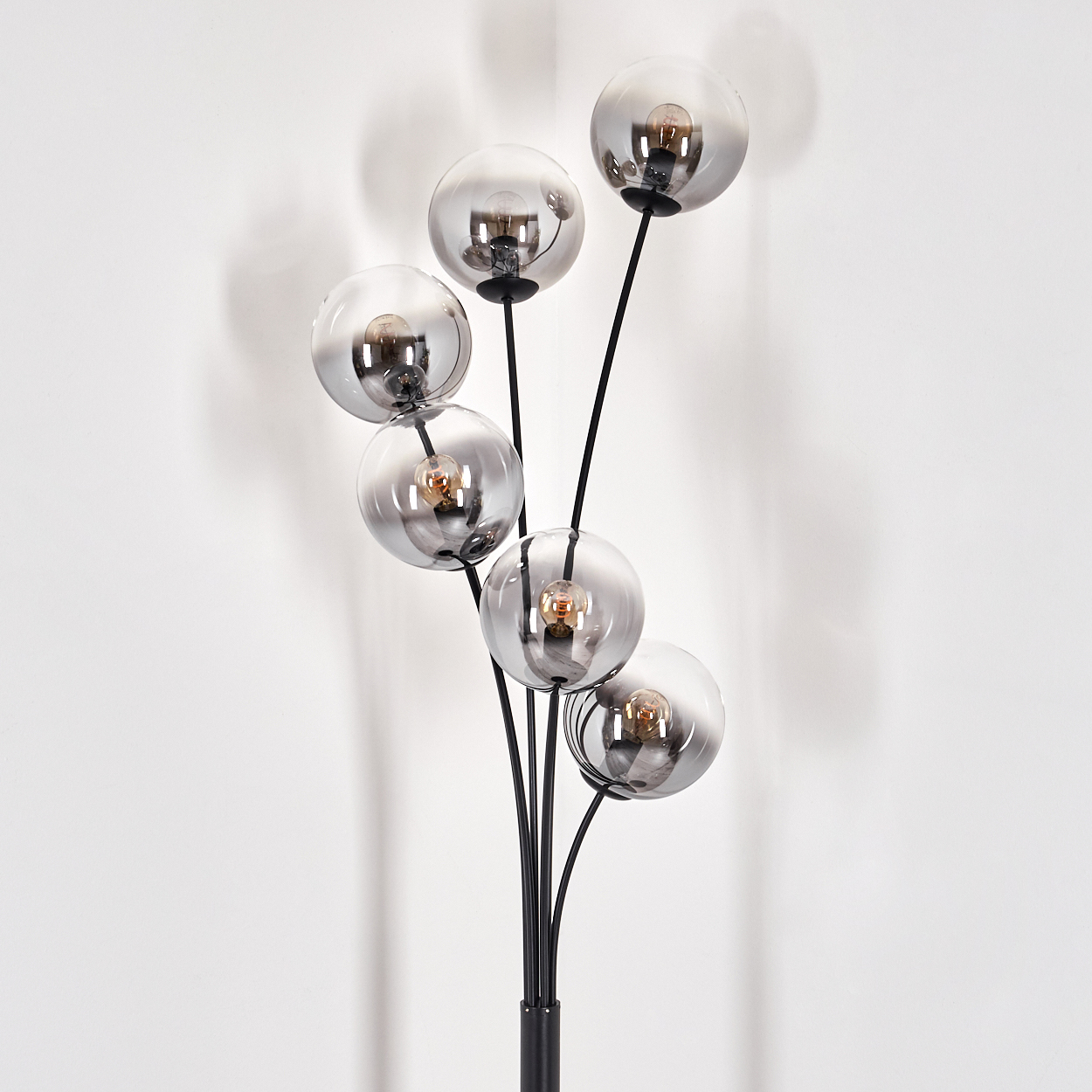 Eine schwarze Stehlampe mit sechs Glasschirmen vor weißem Hintergrund.
