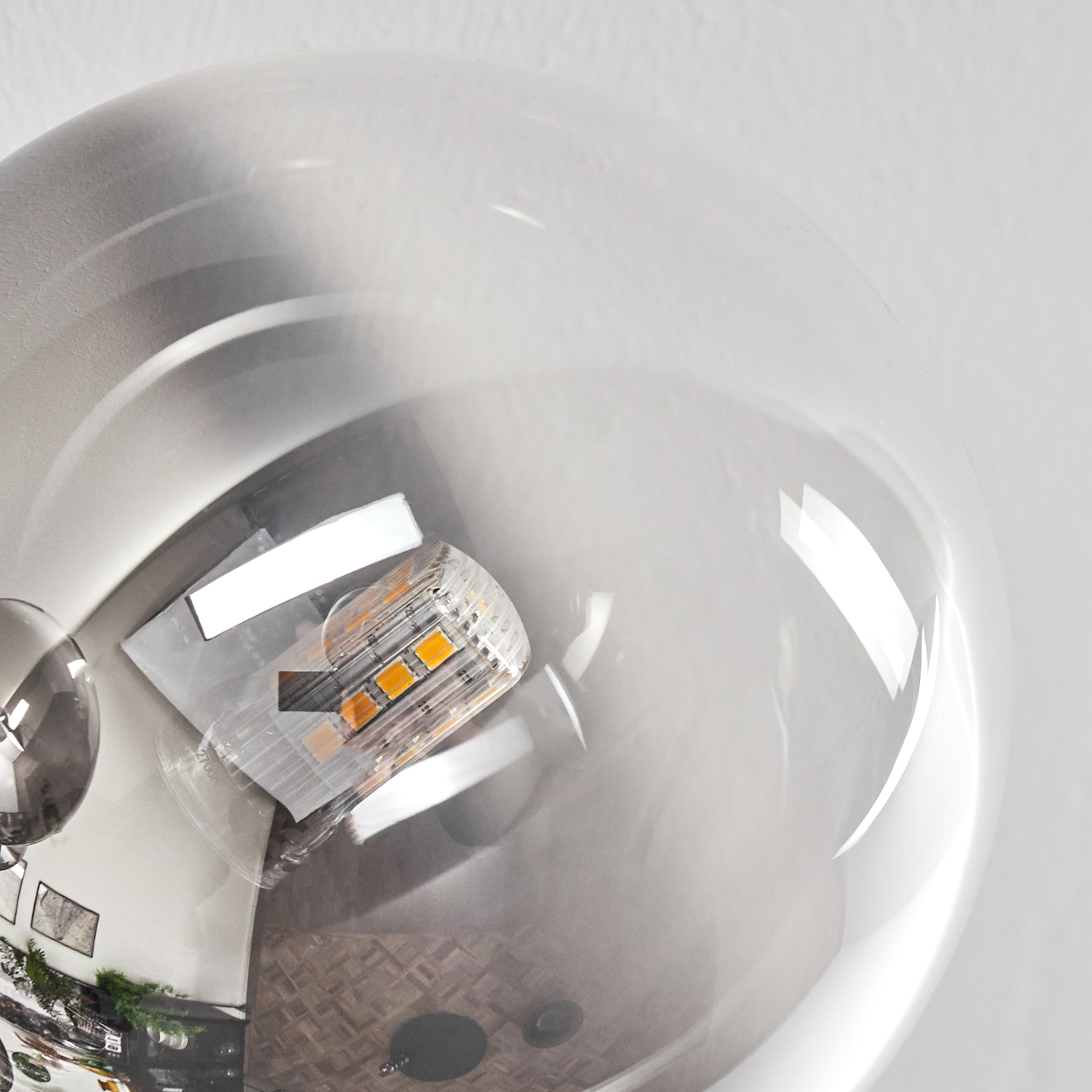 Nahaufnahme einer Glaskugel mit einer Glühbirne im Inneren, die Details eines Raumes widerspiegelt.