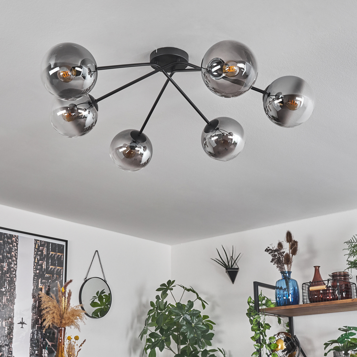 Decke mit Kugellampen, Pflanzen, Regalen und Spiegel. Schwarze Stange und Sockel.