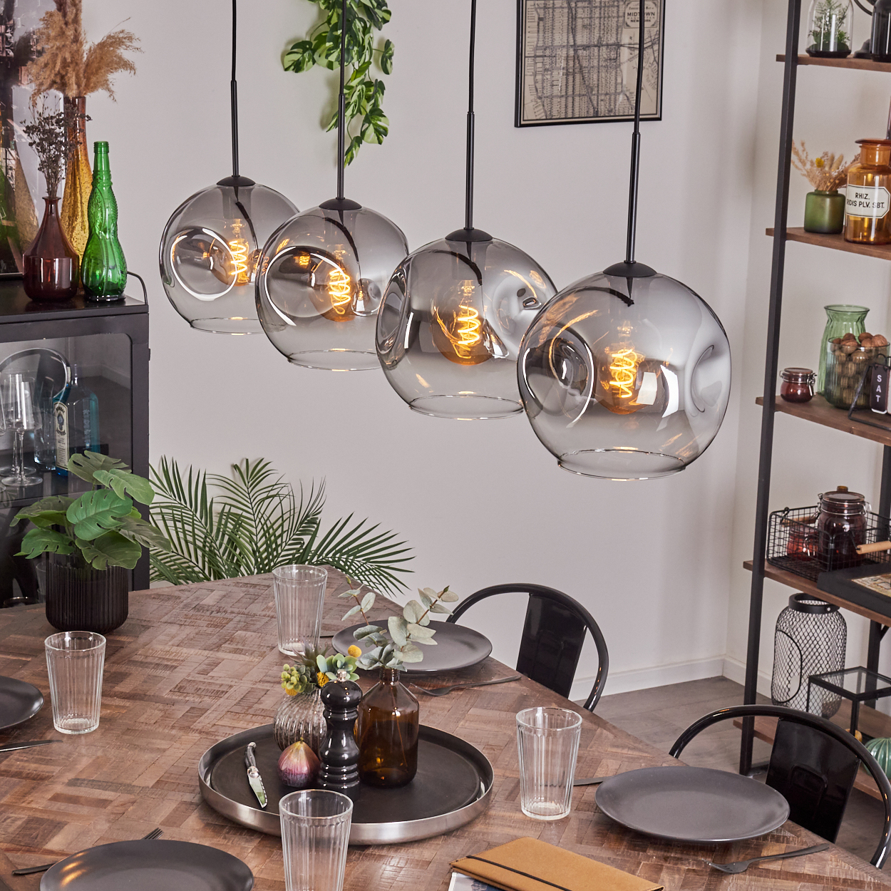 Vier Hängelampen über einem Tisch. Die Lampen sind kugelförmig und die Szene ist dekoriert.