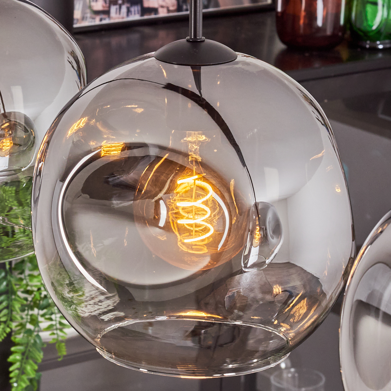 Nahaufnahme einer kugelförmigen Lampe. Die Lampe hat eine Glühbirne im Inneren. Dunkler Hintergrund.