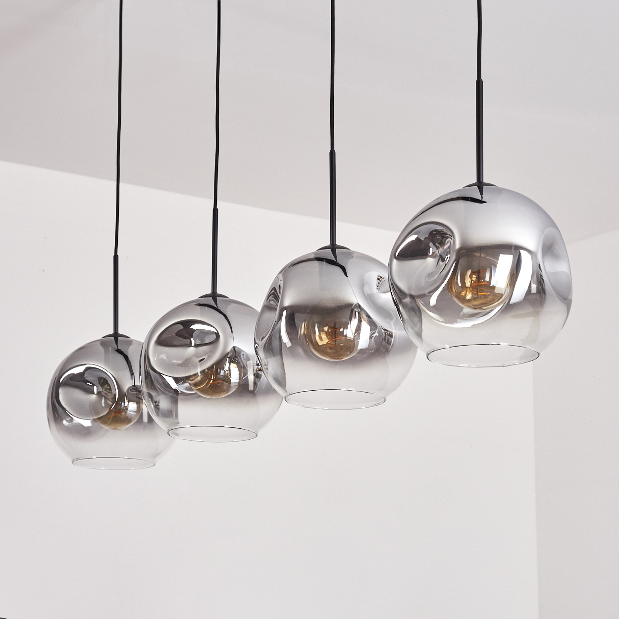 Vier kugelförmige Lampen hängen von der Decke. Die Lampen sind silber und Glas.