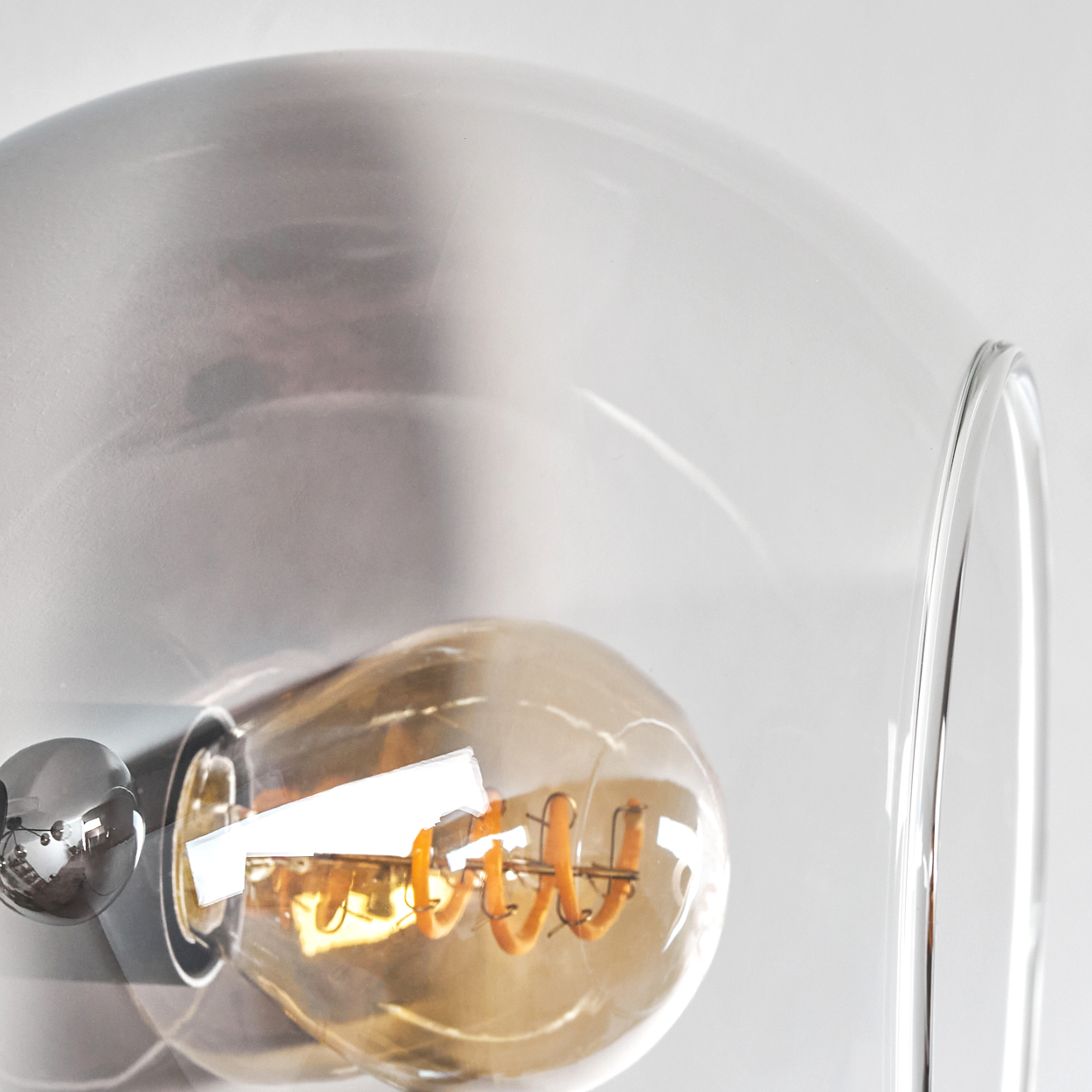 Nahaufnahme einer transparenten Glühbirne, teilweise in einer Glaskugel.