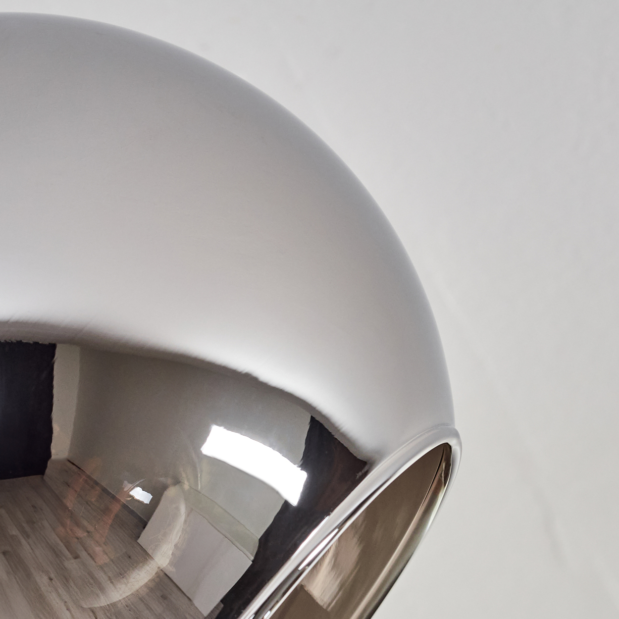 Nahaufnahme einer Chrom-Kugelleuchte. Das Licht reflektiert die Umgebung.