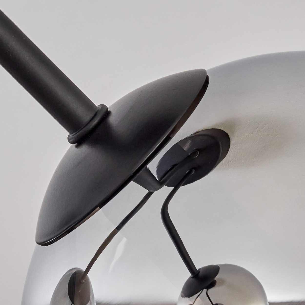 Nahaufnahme einer schwarzen Leuchte mit einer silbernen, kugelförmigen Lampe, die an der Decke befestigt ist.