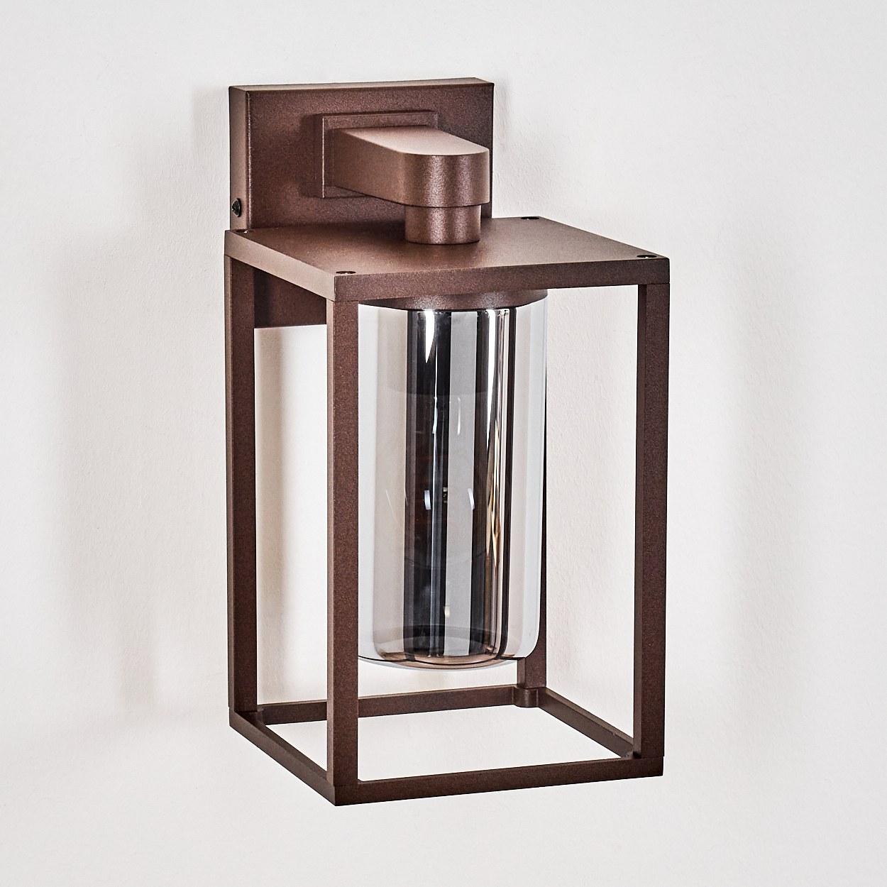 Eine bronzefarbene Außenlampe mit quadratischem Rahmen und klarem, zylindrischem Glas.