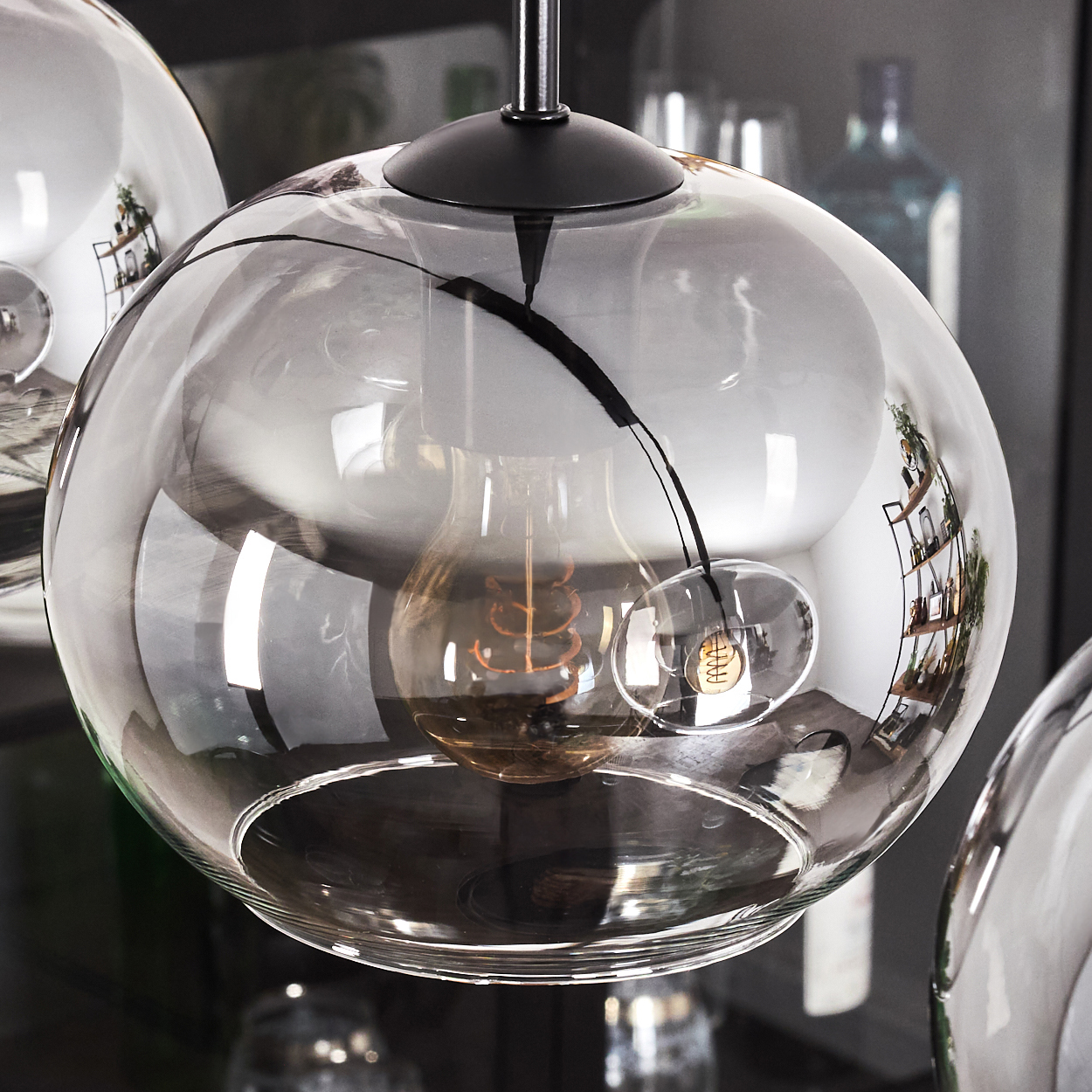 Nahaufnahme eines Glaskugel-Lampenschirms. Im transparenten Glas ist eine sichtbare Glühbirne.