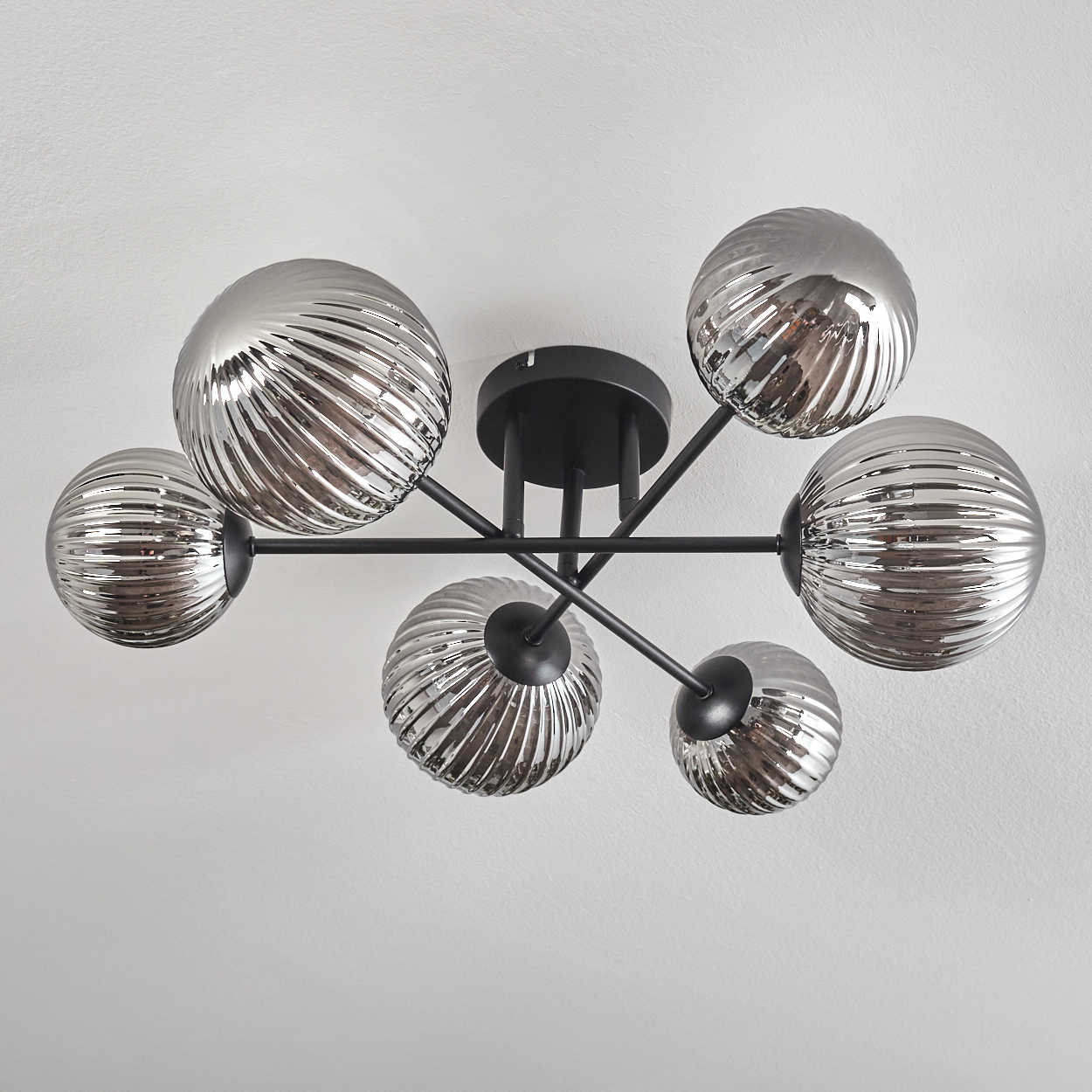 Deckenlampe mit sechs gerippten Glaskugeln vor weißem Hintergrund.