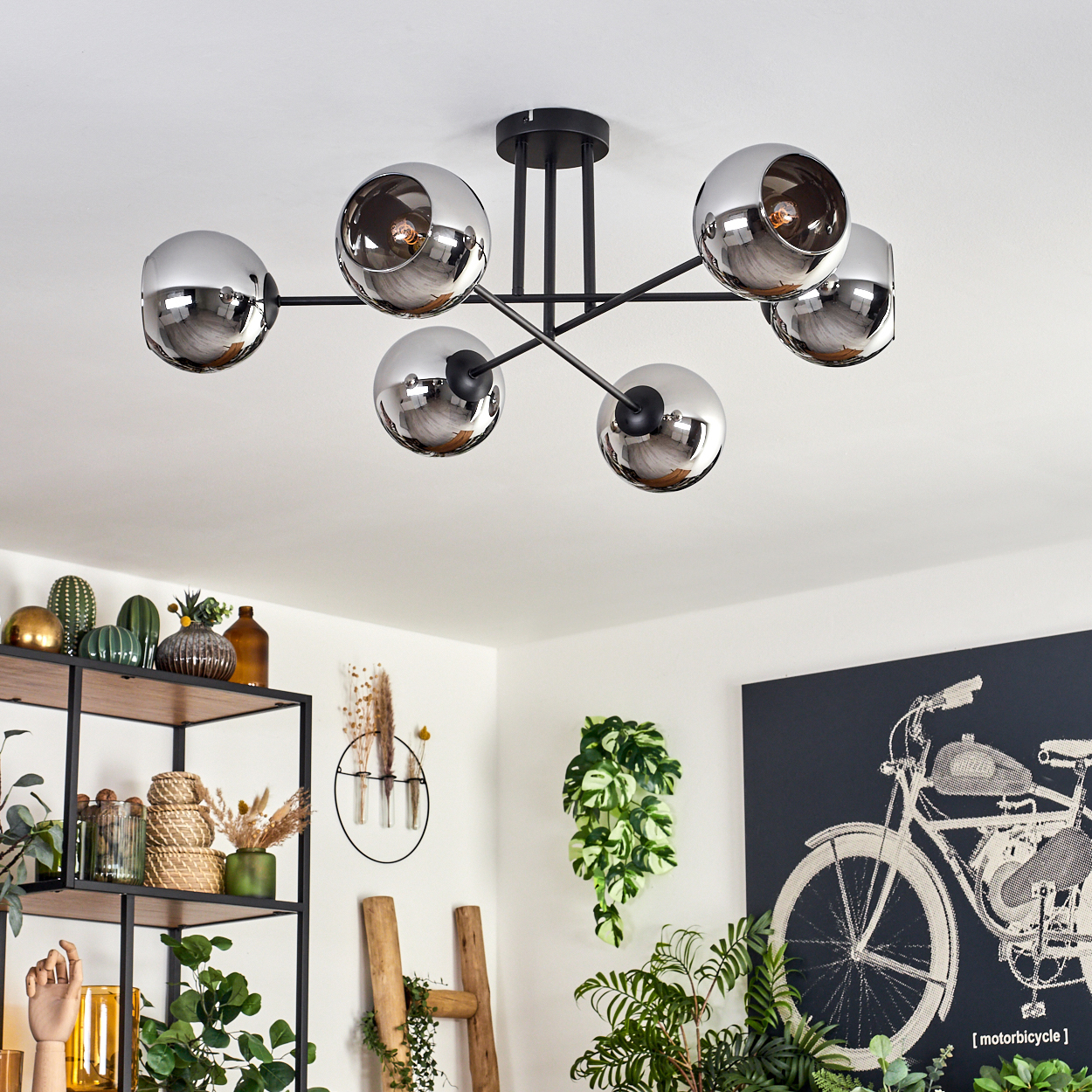 Eine Deckenlampe mit sechs Chromlampen und ein Wohnzimmer mit Pflanzen und Dekorationen.