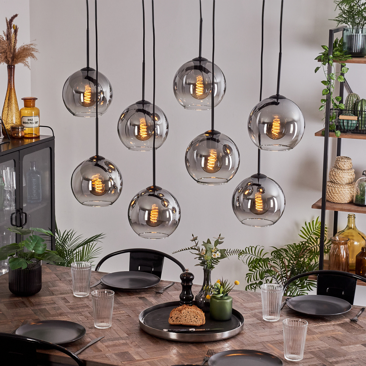 Ein Esstisch mit acht Pendelleuchten. Jede Lampe hat eine runde Form und eine Glühbirne.
