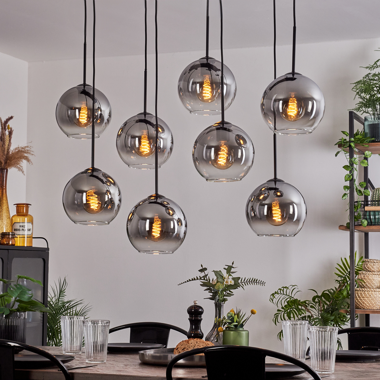 Ein Esszimmer mit einem Holztisch und mehreren hängenden Kugellampen mit sichtbaren Glühbirnen.