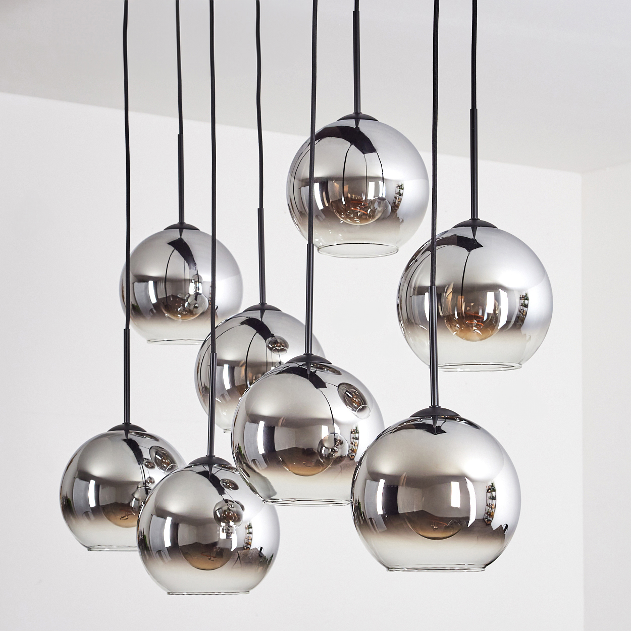 Acht silberne Kugelleuchten, die von einer weißen Decke hängen. Die Lichter sind gleichmäßig verteilt. Der Hintergrund ist weiß.