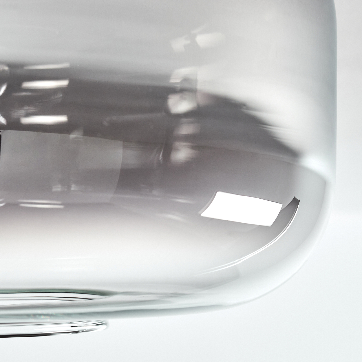 Nahaufnahme eines grauen Glasschirms. Das Glas ist glatt und transparent und reflektiert Licht.