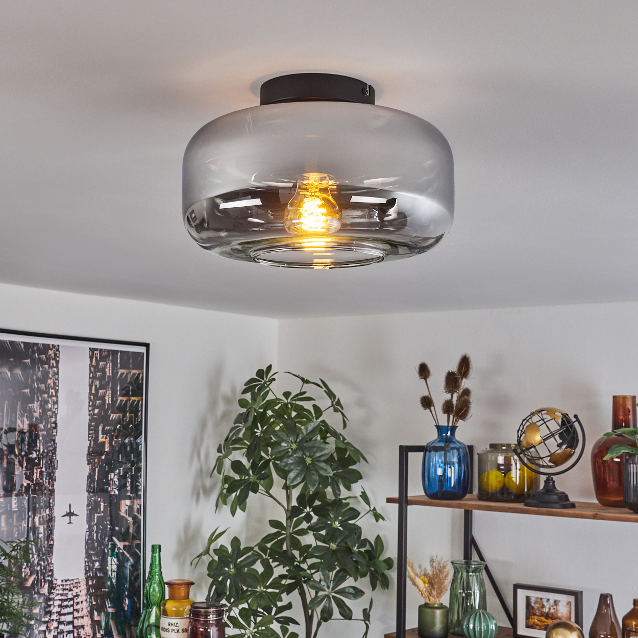 Eine Deckenlampe mit grauem Glasschirm. Die Lampe hat eine kreisförmige Form mit einer sichtbaren Glühbirne im Inneren.