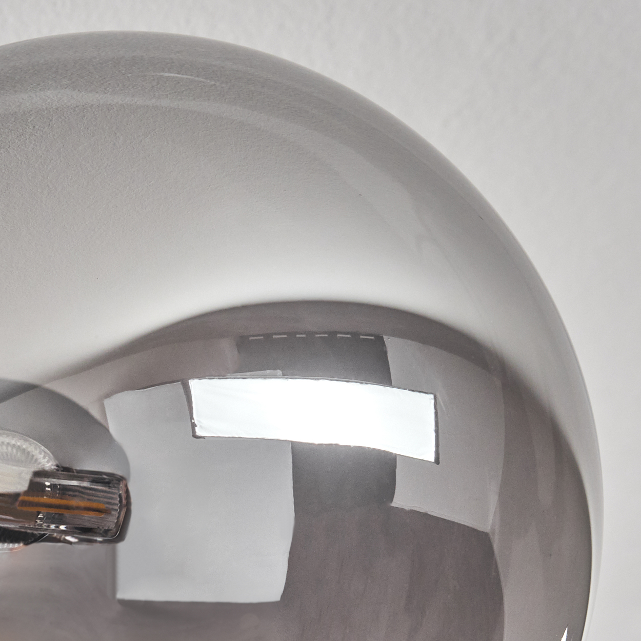 Nahaufnahme der rauchigen Glaskuppel einer Deckenleuchte. Das Licht reflektiert eine helle rechteckige Form.
