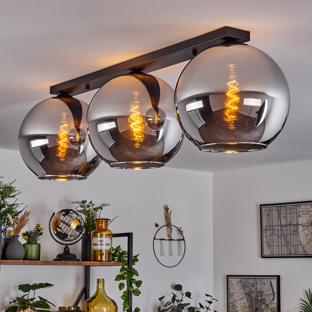 Eine Deckenleuchte mit drei Chromkugelleuchten. Die Lichter sind an, und der Wendel ist sichtbar. Der Raum ist sichtbar.