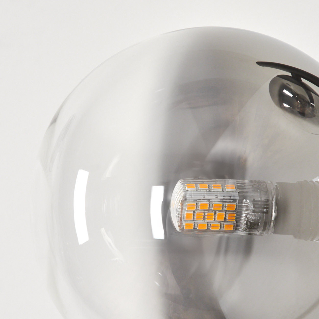 Nahaufnahme einer Glühbirne aus Glas. Die Glühbirne ist klar, mit einem orangefarbenen LED-Licht im Inneren und einem schwarzen Deckel.