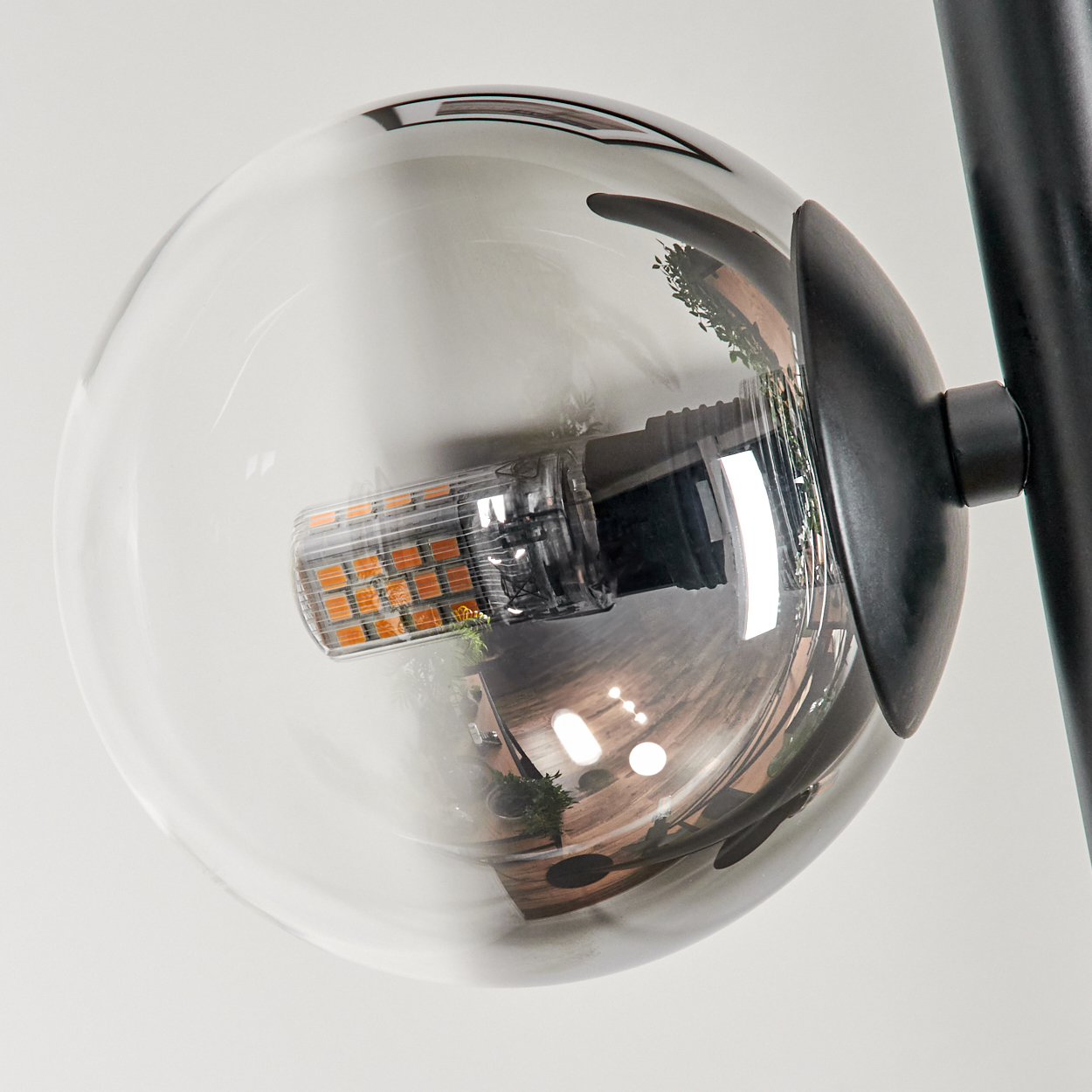 Nahaufnahme einer Glühbirne aus Glas. Die Glühbirne ist klar, das LED-Licht ist an und es gibt eine schwarze Halterung.
