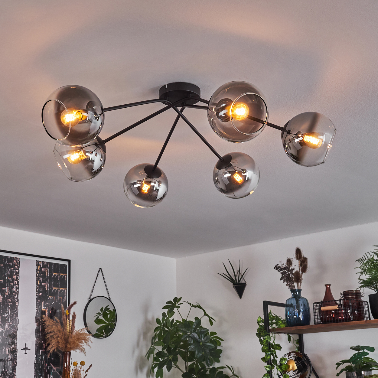 Deckenlampe mit sechs Glaskugeln. Der Raum hat Pflanzen und Deko. Das Licht beleuchtet den Raum.
