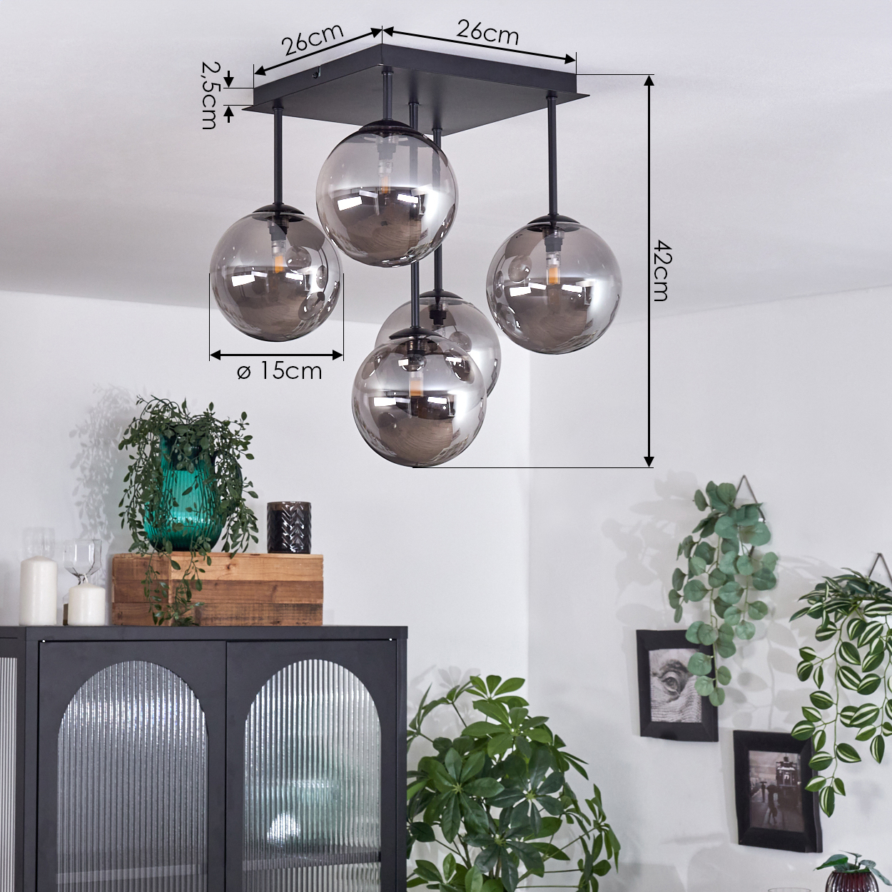 Deckenlampe mit fünf Glaskugeln, Maße angegeben. Pflanzen und Möbel sind ebenfalls sichtbar.