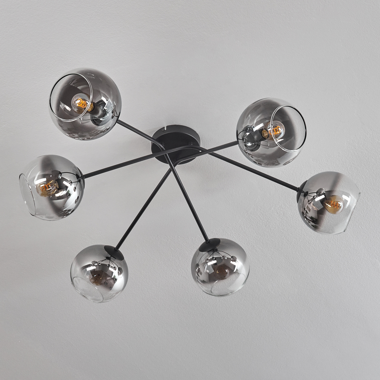 Deckenlampe mit sechs Glaskugeln. Die Glühbirnen sind in den transparenten Kugeln sichtbar.