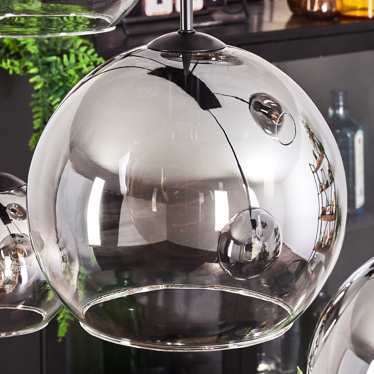 Nahaufnahme einer kugelförmigen Glaslampe mit schwarzem Stiel. Die Lampe ist transparent mit einer reflektierenden Oberfläche.