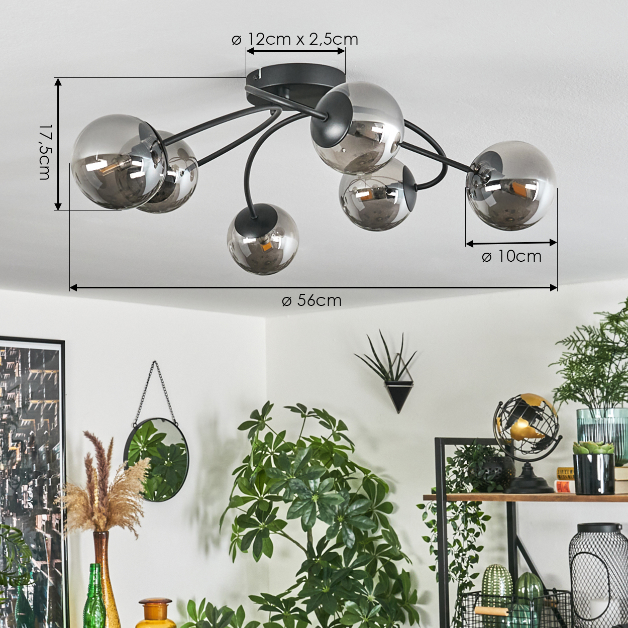 Eine Deckenlampe mit sechs kugelförmigen Glaslampen. Abmessungen sind angegeben. Die Lampe ist über Pflanzen und Dekoration.