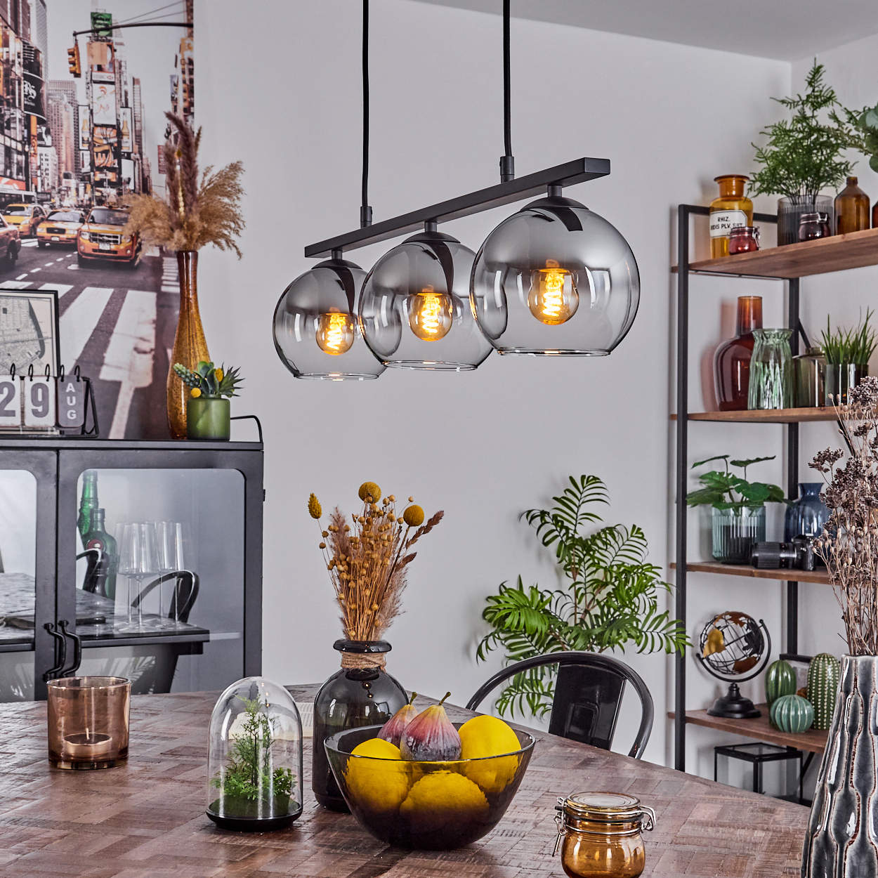 Esszimmer mit Esstisch und schwarzer Lampe mit drei Glaskugeln.