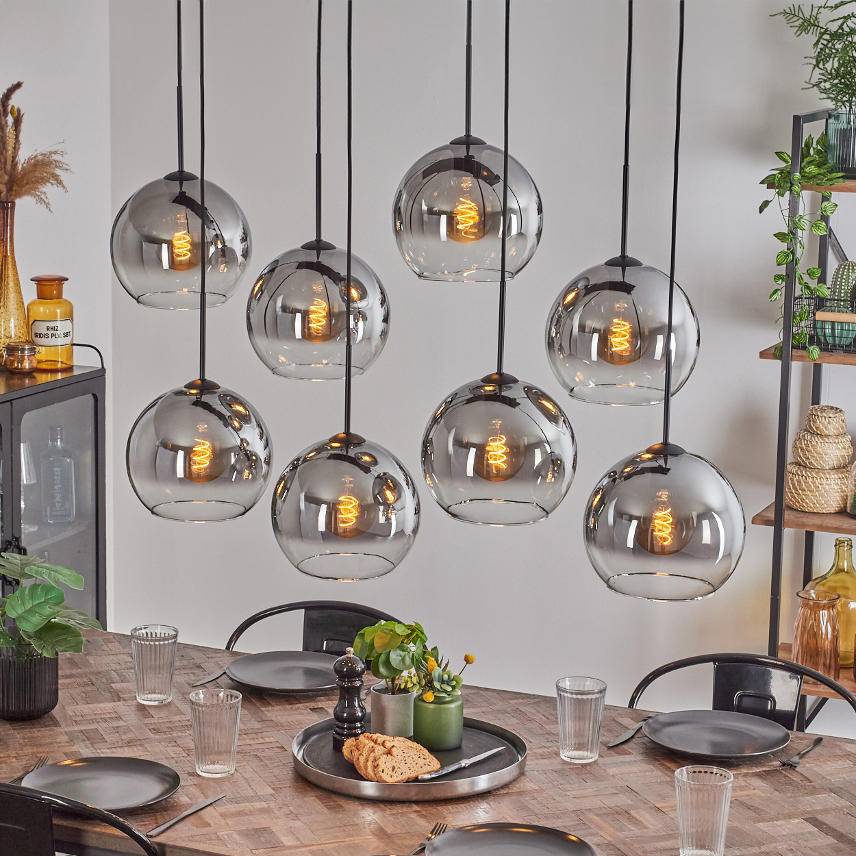 Esszimmer mit Holztisch und schwarzer Leuchte mit acht silbernen Kugelleuchten.