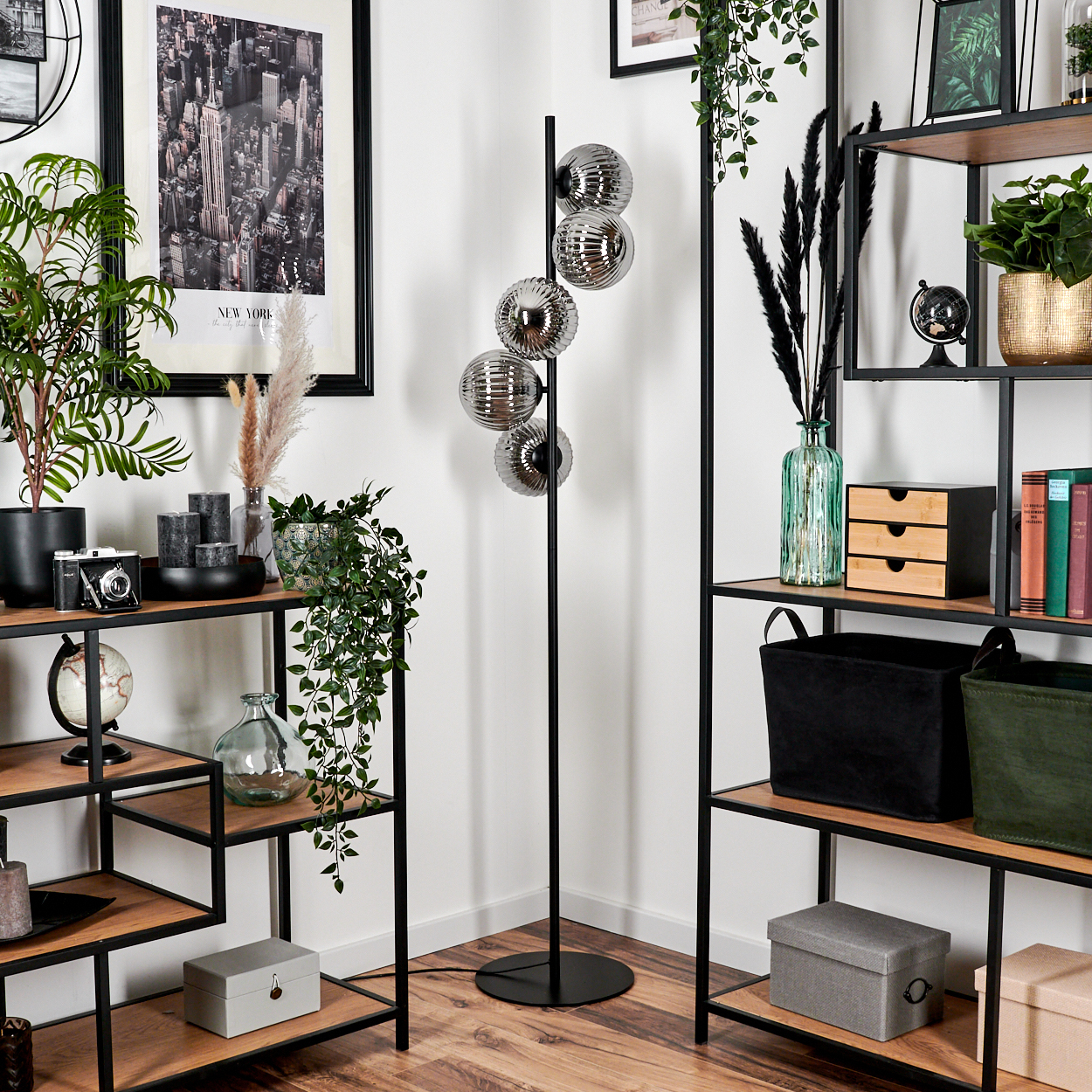 Eine Ecke mit Stehlampe, Regalen, Pflanzen und Dekoration.