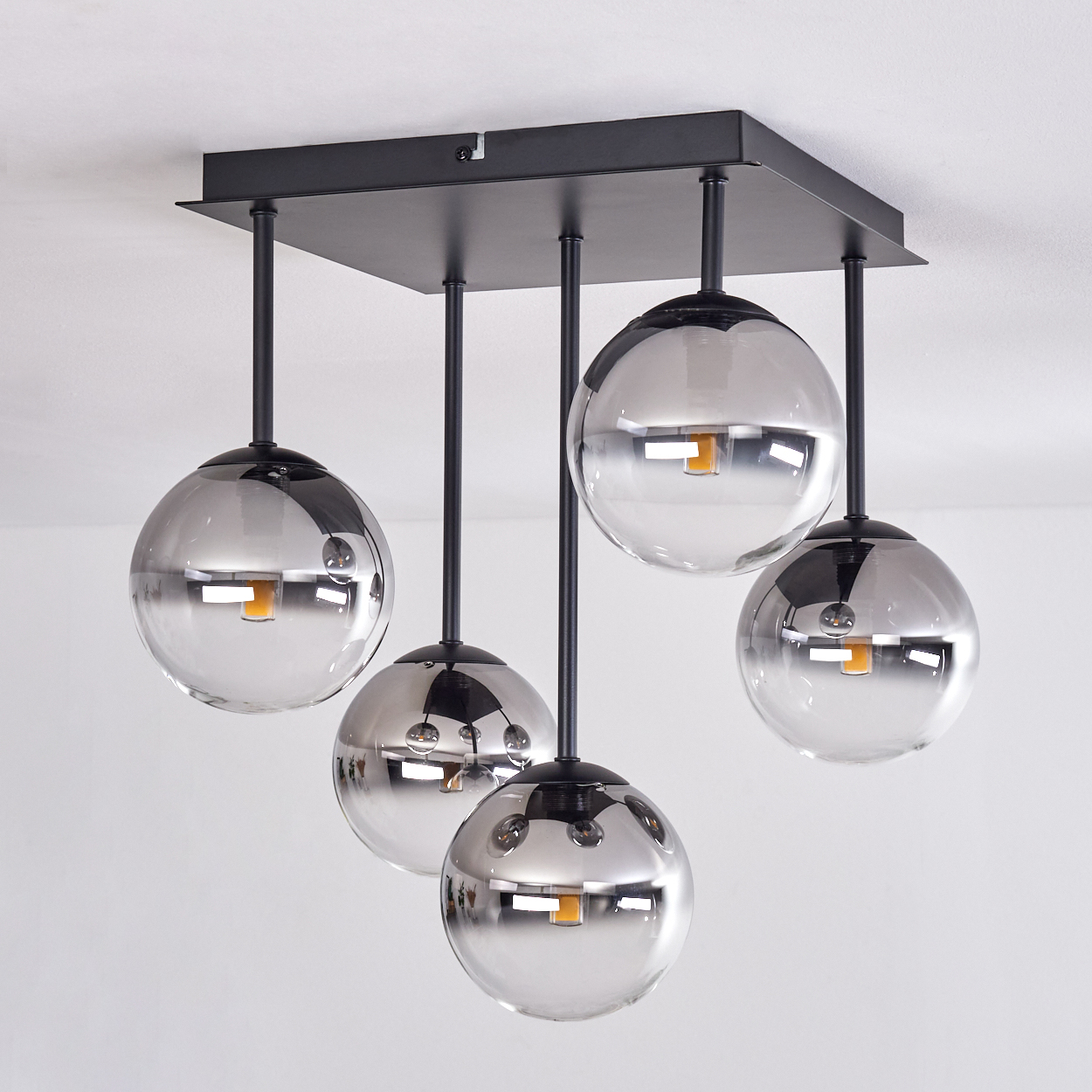 Fünf kugelförmige, klare Glas-Pendelleuchten, die von einer schwarzen Deckenhalterung hängen.